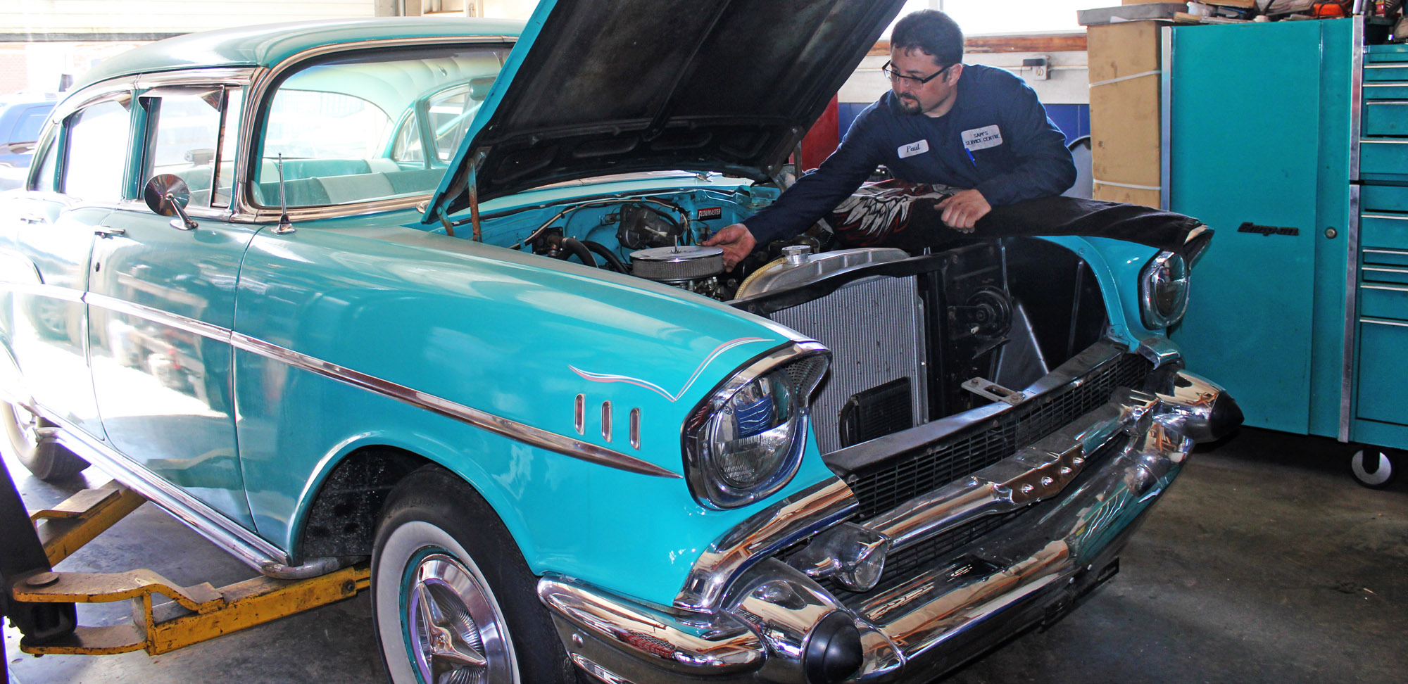 Paul from Sam's Service Centre working on the engine of a '57 Chevy, a restoration project